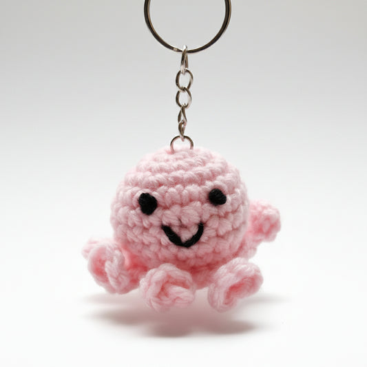 Pink crochet octopus keychain attached to a keyring with a blurred background