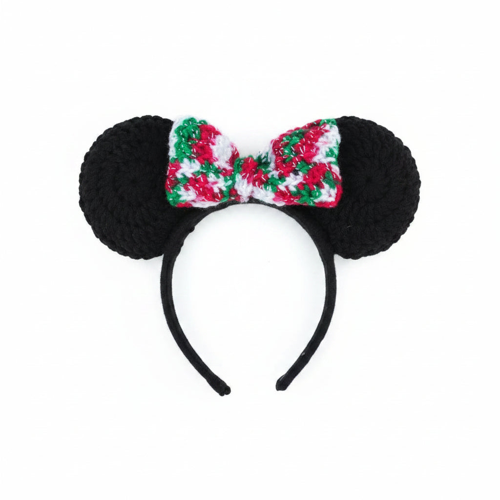 Black mouse ears with a colorful bow tie held over pebbles