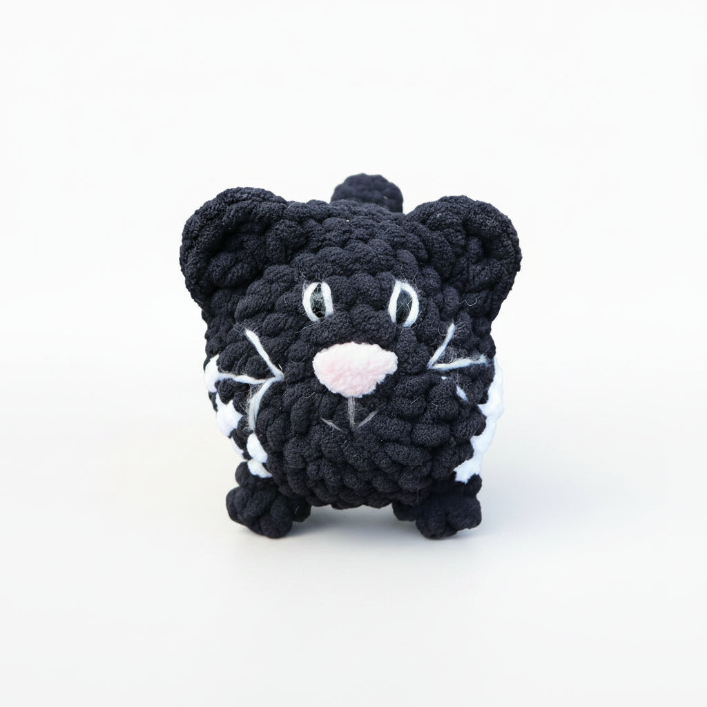  black and white cat crocheted with a grassy background