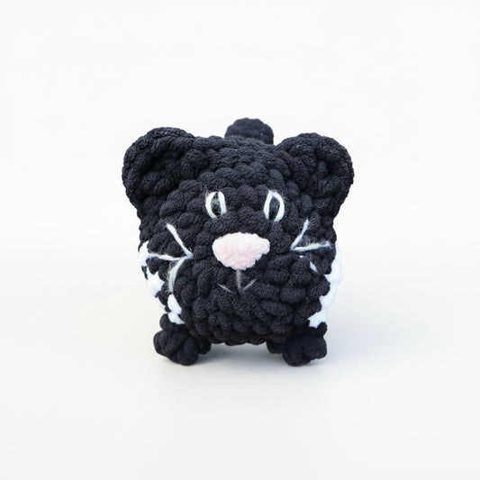  black and white cat crocheted with a grassy background