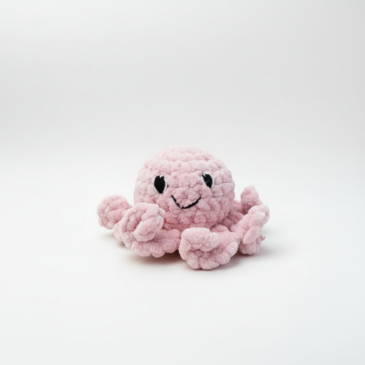 Pink plush octopus toy held in a hand with a blurred natural background
