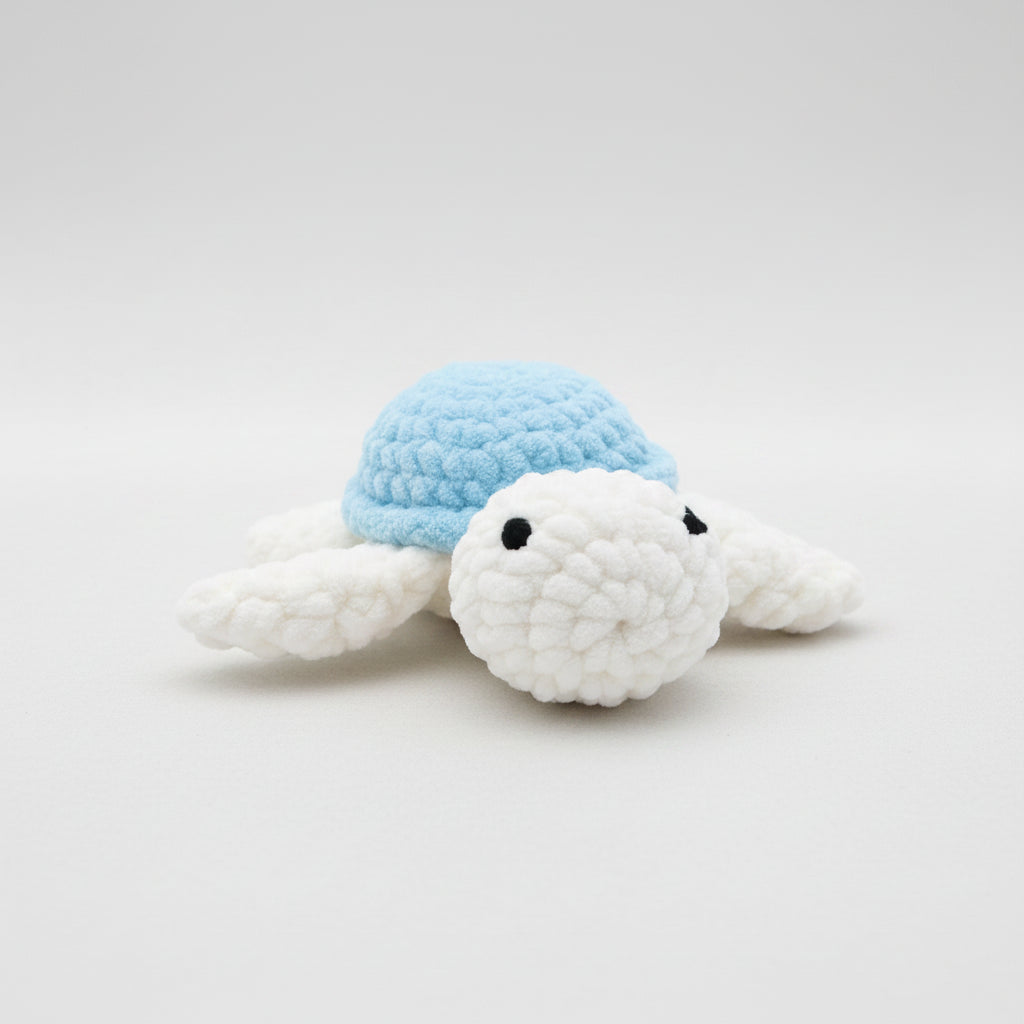 Hand holding a crochet turtle against a grassy background