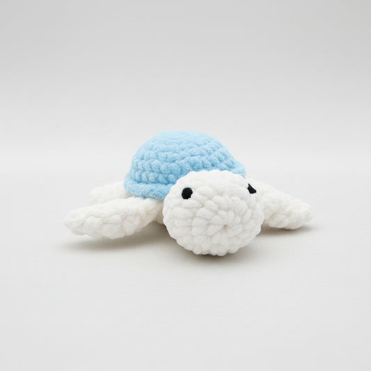 Hand holding a crochet turtle against a grassy background