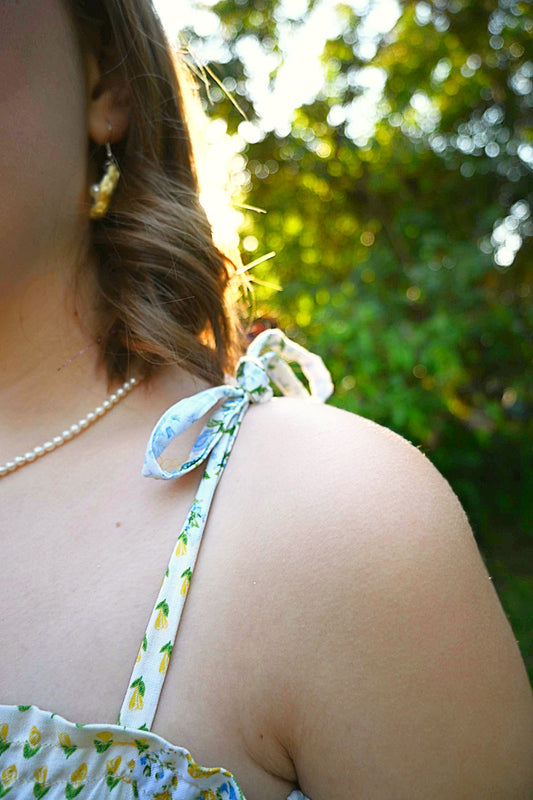 Close-up of a person wearing a floral top with a bow on an outdoor setting
