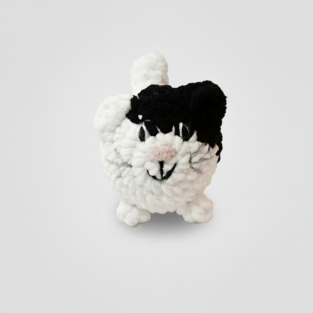 Crocheted black and white cat on a light background