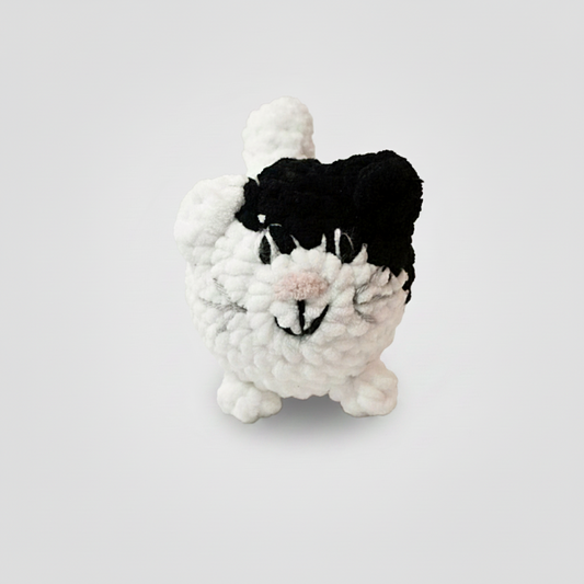 Crocheted black and white cat on a light background
