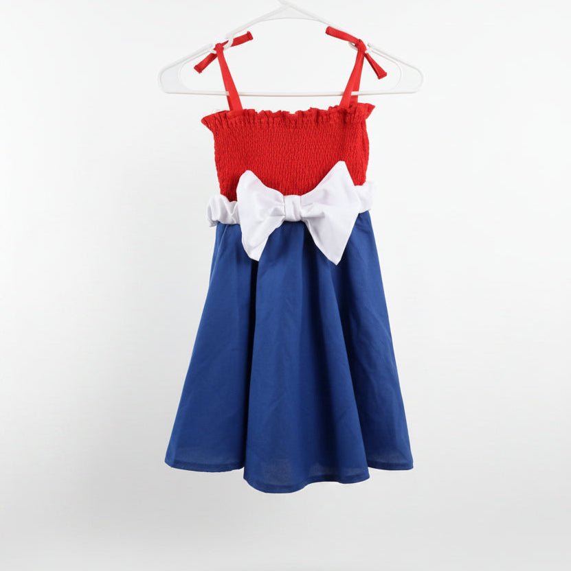 Red and blue dress with a white bow on a hanger against a white background